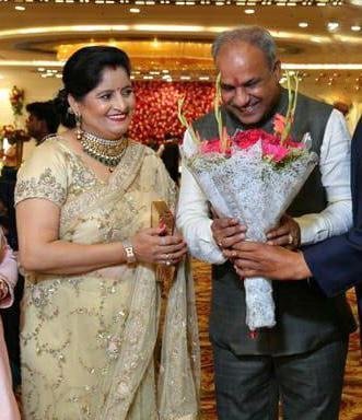 indian man recieving flower bouquet standind along his wife